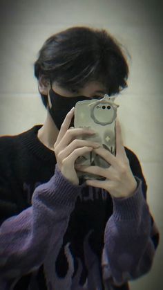 a person taking a selfie in front of a mirror wearing a black face mask