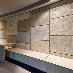 an empty bench in front of a wall made out of stone blocks and concrete tiles