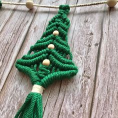 a green christmas tree ornament hanging from a string on a wooden surface with white beads