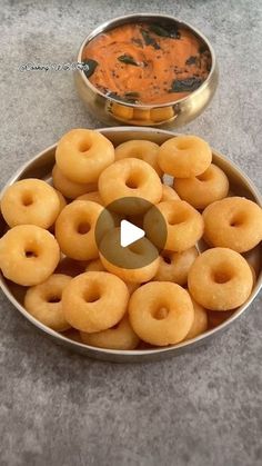 a bowl full of doughnuts next to a metal pan filled with dipping sauce