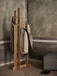 a coat rack with two coats hanging on it next to a black and white checkered ottoman