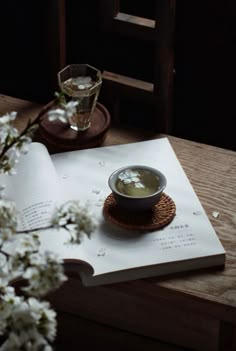 an open book on a table next to a bowl of soup