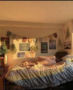 an unmade bed sitting in a bedroom next to a plant filled wall with pictures on it