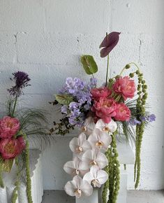 three white vases with flowers and plants in them