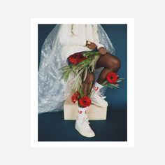 a woman sitting on top of a wooden block with flowers in front of her legs