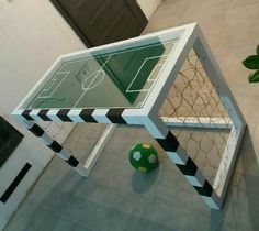 a soccer ball sitting on the ground next to a glass table with an upside down goal