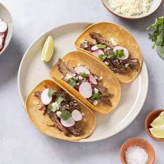 three tacos with meat, radishes and cilantro on a plate