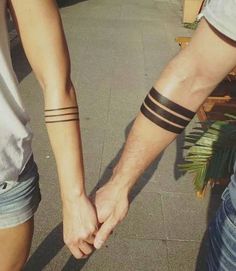 two people holding hands with tattoos on their arms