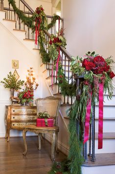 a staircase decorated with christmas greenery and red bows