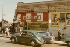 an old car parked in front of a ice cream shop on the side of a street