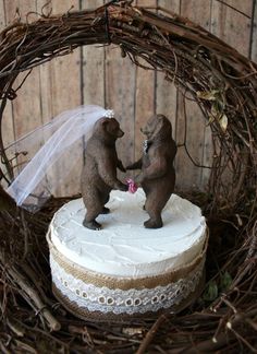 two brown bears standing on top of a white cake in a bird's nest