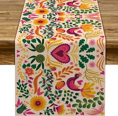 an image of a table runner with flowers and paisley designs on the top, along with wooden planks