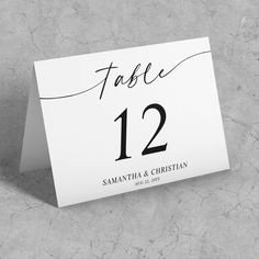 a place card with the number twelve on it is placed next to a marble surface