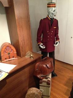 a mannequin dressed in a red jacket and hat next to suitcases