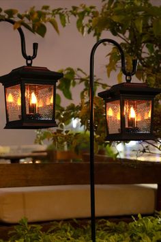 two hanging lanterns with lit candles in them