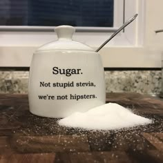 a salt shaker sitting on top of a wooden table next to a pile of sugar