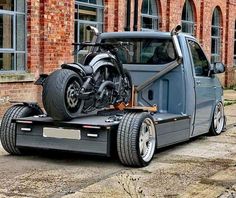 a motorcycle is on the back of a flatbed tow truck in front of a brick building