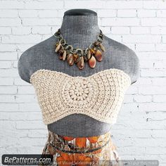 a mannequin wearing a crochet top and necklace