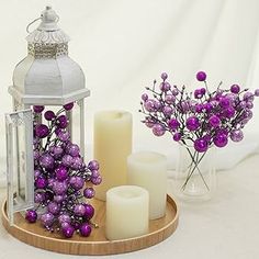 purple flowers and candles are on a tray with a candle holder in the background,