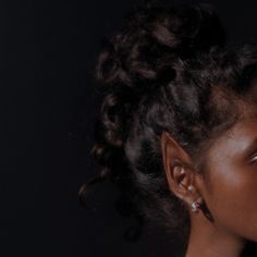 a close up of a person with curly hair and an earring on her head