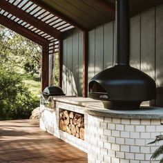 a wood burning stove sitting on top of a white brick wall next to a forest