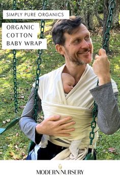 A father using The Simply Pure Organic Cotton Baby Wrap to hold up their baby while they sit down on the swings of a playground.