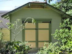 a small green building with two doors and windows