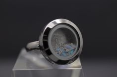 "This unisex customizable cremation ash locket ring is new to our collection of fill-at-home cremation pieces. Your purchase includes the silver ring and opal color of your choice and does not require mailing the ashes. It is composed of sturdy glass and stainless steel (hypoallergenic, scratch/tarnish resistant). The circle is 20mm across with the window being 12mm. The sturdy band is 4mm wide. The ring ships with your choice of synthetic crushed opal (over 90 colors to choose from). After adding ashes, sand, dried funeral flowers, etc., simply screw the front portion in place. For added security, we recommend adding a drop or two of superglue once you've added your inclusions. For your convenience, you have the option to purchase a single-use tube of superglue via the drop-down menu. All Ashes Jewelry Cremation Spirit Piece Memorials, Ashes Ring 1stdibs, Rings For Ashes Sterling Silver, Ashes In Resin Sterling Silver, Memorial Jewelry Ashes Men, Ashes Ring Gold, Ashes In Resin Ring, Resin Necklace With Ashes, Ash Rings Cremation Jewelry