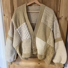 a beige and white sweater hanging on a wooden door