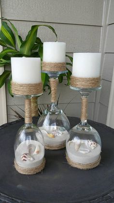 three glass vases filled with sand and sea shells sitting on top of a table