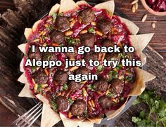 a pizza sitting on top of a wooden table next to a fork and bowl filled with food