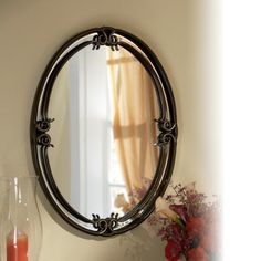 a round mirror sitting on top of a table next to a vase filled with flowers