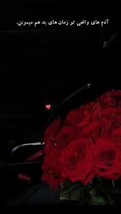 a bouquet of red roses sitting on top of a black table next to a car