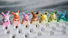 a row of small toy figurines sitting on top of a computer keyboard with pikachu and eebi