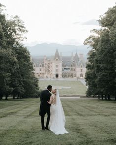 a bride and groom standing in front of a castle