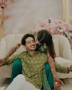 a man and woman sitting next to each other in front of a flower covered wall