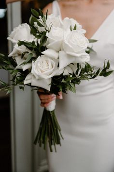 a bride holding a bouquet of white roses