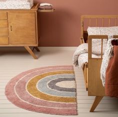 a child's bedroom with pink walls and wooden furniture, including a crib