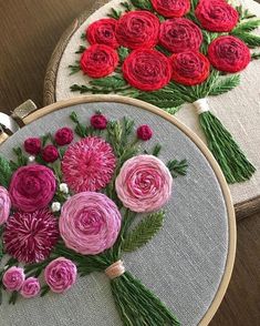 two embroidery hoops with flowers on them, one is pink and the other is red