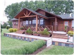 a wooden house sitting on top of a lush green field