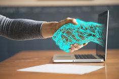 two people shaking hands in front of a laptop with an image of a brain on the screen