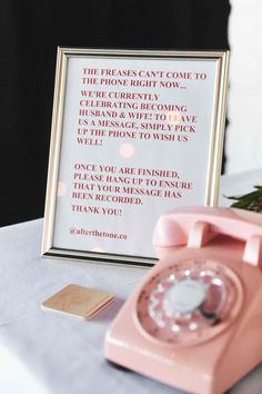 a pink phone sitting on top of a table next to a framed sign that says, the press can't come to you