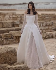 a woman in a white wedding dress standing on rocks