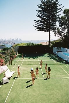 several women in bathing suits playing tennis on a grass court