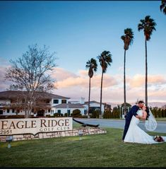 a bride and groom kissing in front of the eagle ridge golf club sign at sunset