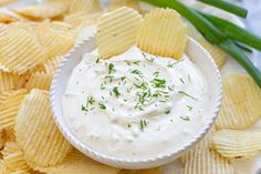 a white bowl filled with dip surrounded by chips