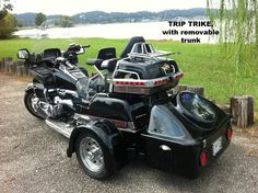 a black motorcycle parked on the side of a road next to a lake and trees