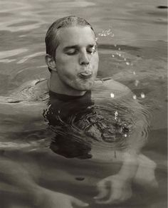 an old photo of a man swimming in the water with his mouth open and tongue out