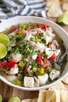 a white bowl filled with fish and vegetables next to tortilla chips