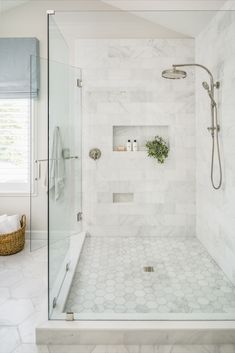 a walk in shower sitting next to a white tiled wall and floor with a plant on the ledge